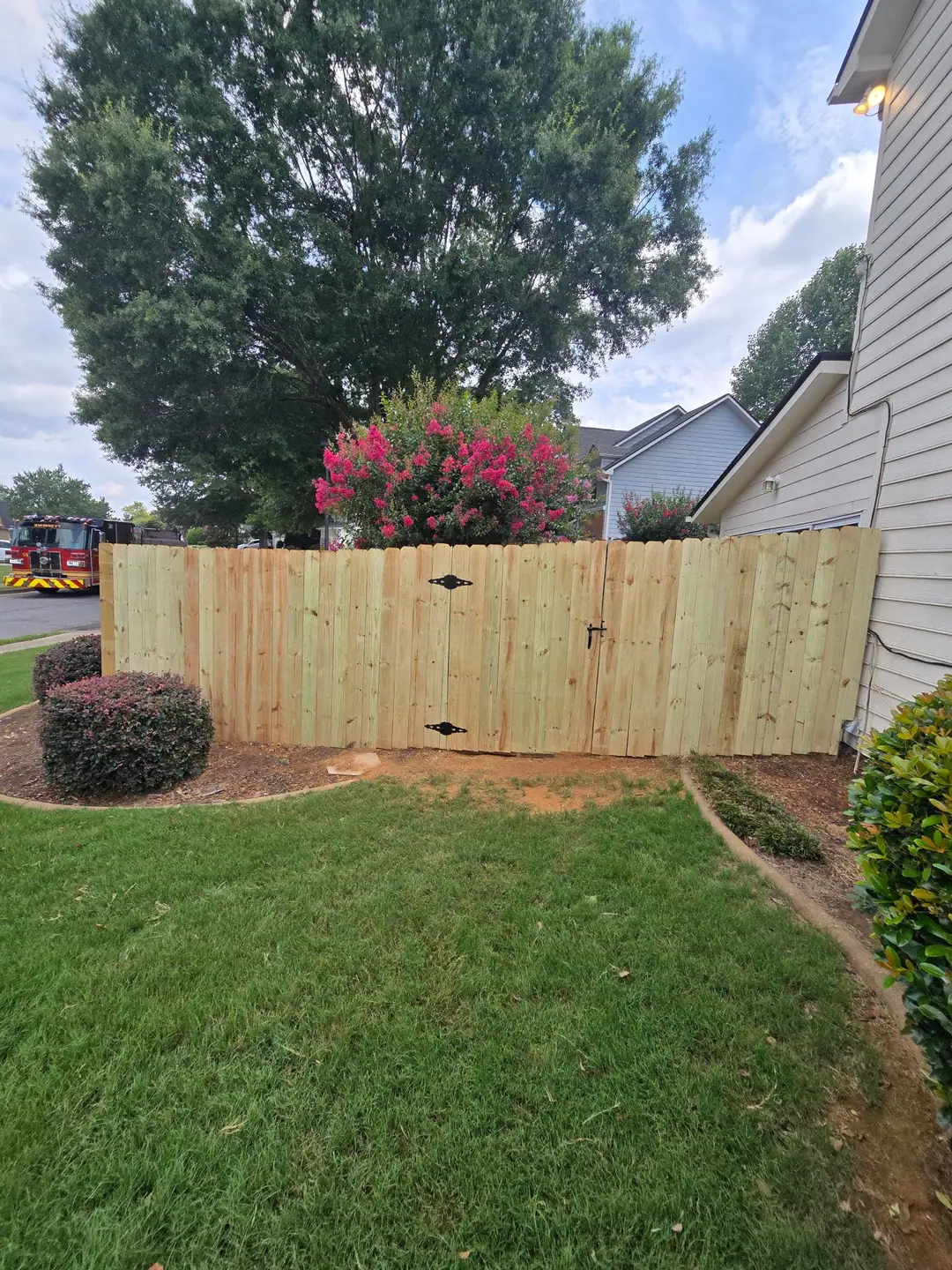 Done: a new wood privacy fence with a double gate and black hinges closing the side yard