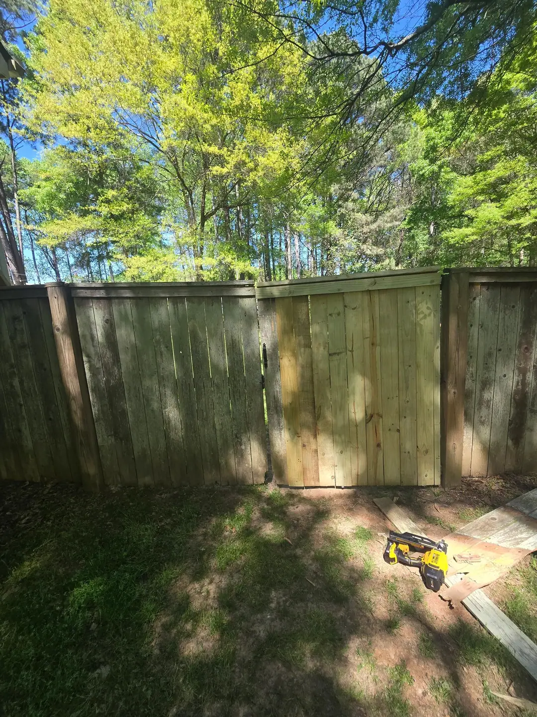 New wood fence section installed between older weathered panels