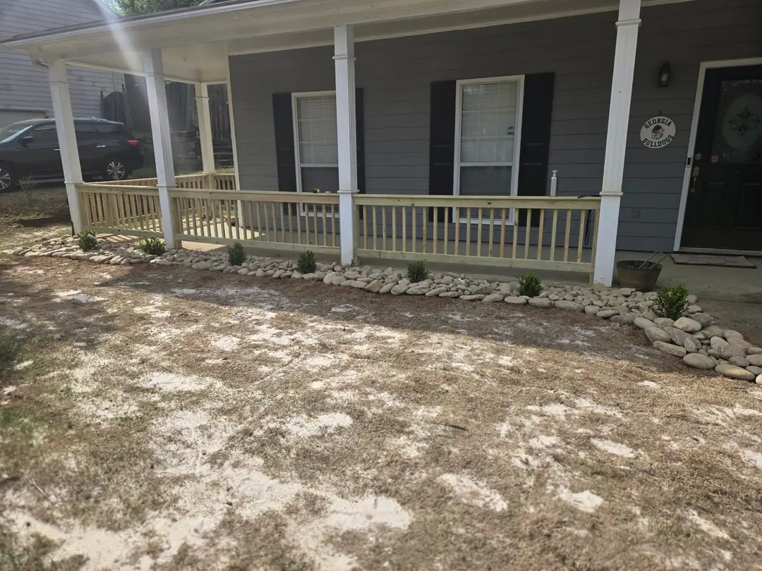 New wood porch railing between white columns on a gray house