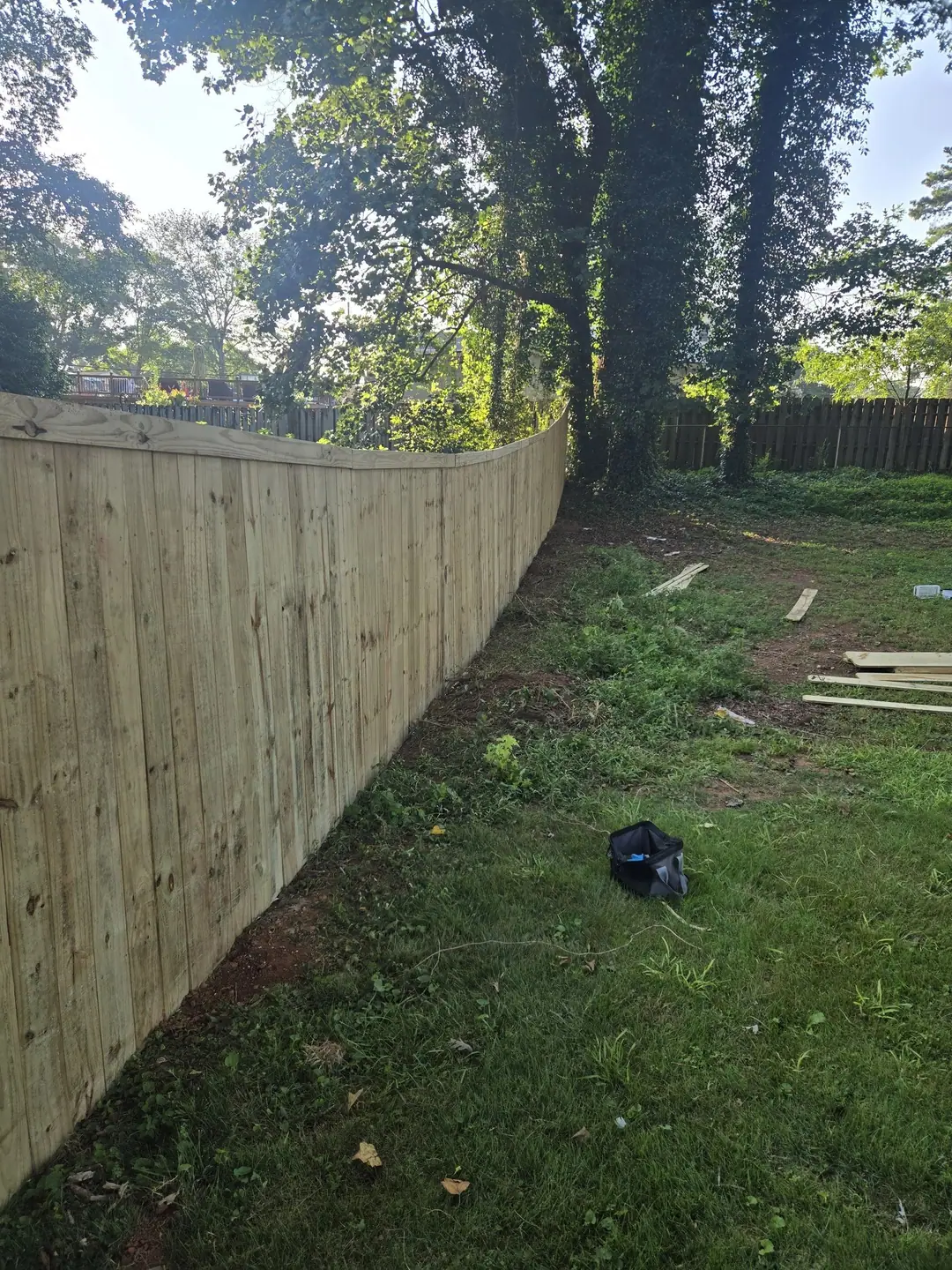 Long wood privacy fence following the curve of a backyard lawn